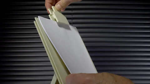 Hands securing plain white paper to an upright clipboard. Stock Footage 244578336