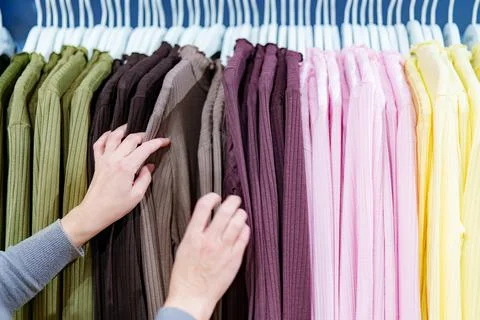 Hands select clothes from rack in store during shopping trip for casual wea.. 库存照片