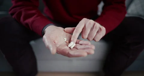 Hands selecting mixed pills and capsules in a quiet indoor setting 스톡 동영상 336286581