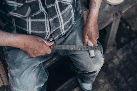 Hands of a senior carpenter working on a piece of wood with a file Stock Photos