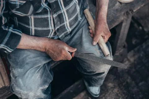 Hands of a senior carpenter working on a piece of wood with a file Stock Photos