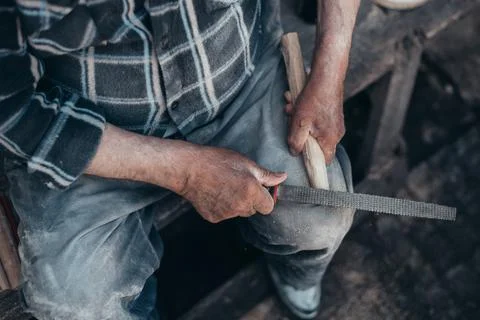 Hands of a senior carpenter working on a piece of wood with a file Stock Photos