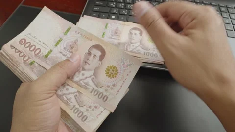 Hands separate new and older version of thousands Thai baht banknotes money. Stock Footage 237687400