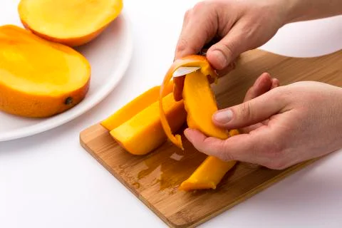 Hands separating mango fruit flesh from its skin Stock Photos