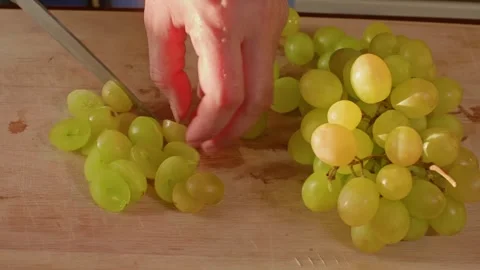 Hands separating white grapes into groups on wooden cutting board 库存影片 344728848