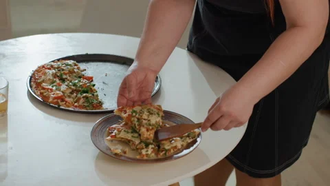 Hands serving and slicing pizza on white round table during casual home meal Stock Footage 343682618