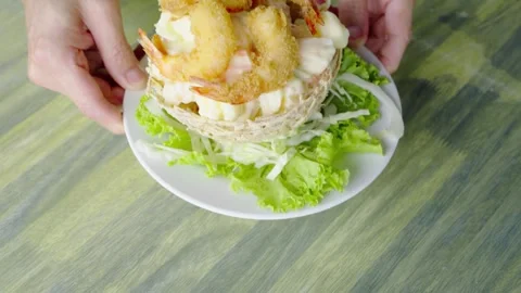 Hands serving crispy fried shrimp in an edible bird nest basket with fruit .. Stock Footage 331452899