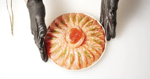 Hands serving a dish of daikon salad and slices of salmon with red caviar Stock Footage 134278550
