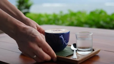 Hands serving espresso macchiato with complimentary cookie on wooden tray Stock Footage 146784593