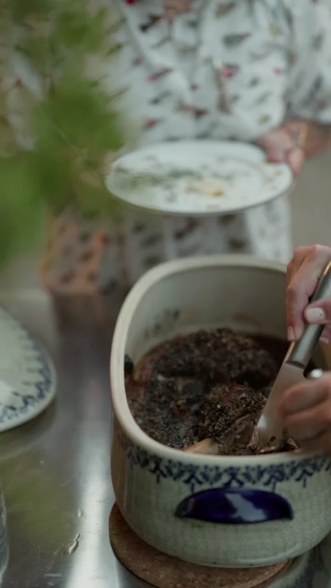 Hands serving homemade food from ceramic pot during intimate dining at table Stock Footage 345266573