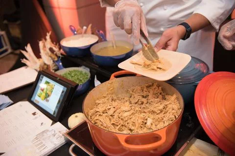 Hands serving pulled chicken onto small plate. Stock Photos