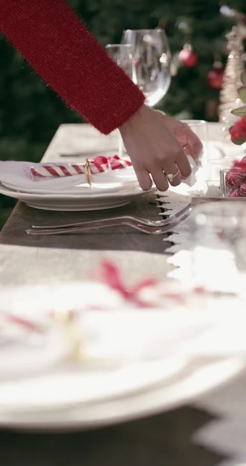 Hands, setting table and outdoor at Christmas for lunch, candy cane or plates Stock Footage 329747256