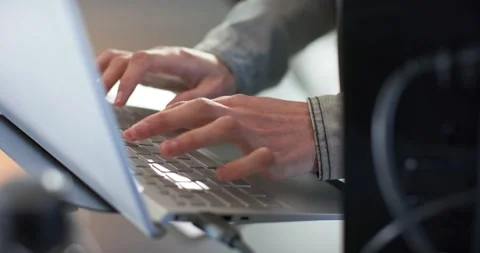 Hands settling on laptop keyboard at desk are typing code steadily for Stock Footage 341937474