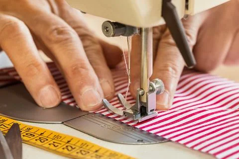 Hands at sewing machine holding some fabric Stock Photos
