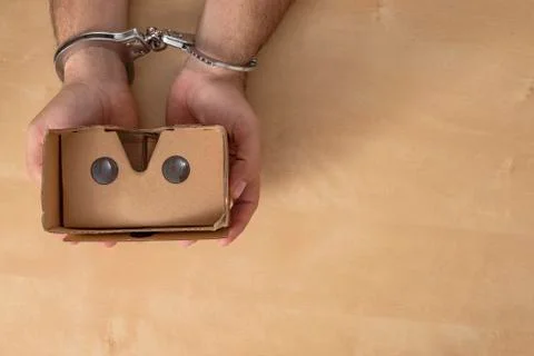 Hands in shackles grabbing some virtual reality glasses. Stock Photos