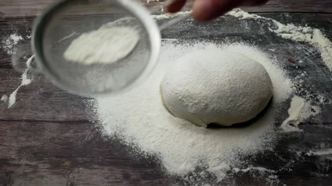 Hands shake the sieve over the dough, sift the flour to make the dough on a Stock Footage 241829028
