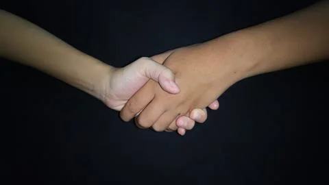 Hands shaking between a man and a woman. Isolated on black background 写真素材
