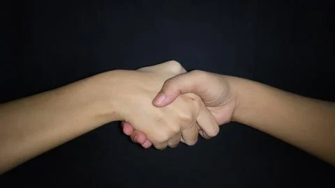 Hands shaking between a man and a woman. Isolated on black background Stock Photos