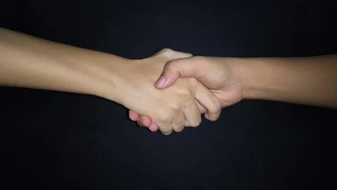 Hands shaking between a man and a woman. Isolated on black background Stock Photos