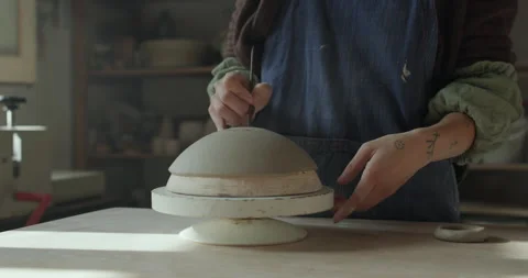 Hands shape a clay dome on a rotating wheel, refining its form. The pottery Stock Footage 301455484