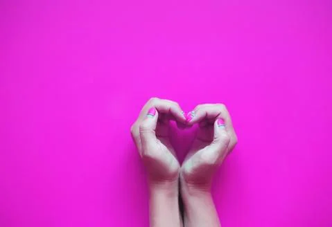 Hands in the shape of a heart on a pink background Foto stock