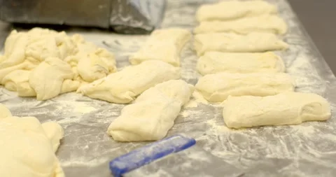 Hands shaping and arranging raw dough portions on floured bakery work surface Vidéo 344596287
