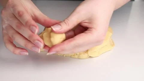 Hands shaping cookie dough on a white surface. Homemade baking preparation with Video stock 303589583