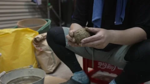 Hands Shaping a Damp Earth Ball Above a Paper Sack Stock Footage 340901125