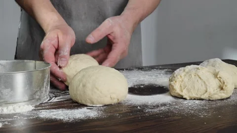 Hands shaping dough into round loaves for homemade bread on floured table Stock Footage 310337361