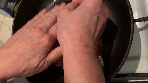 Hands shaping raw ground beef patty in frying pan, close-up cooking detail Stock Footage 344422020