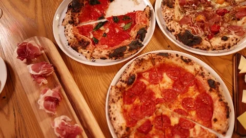 Hands Sharing Fresh Neapolitan Pizzas and Prosciutto on Wooden Table 스톡 동영상 339514004