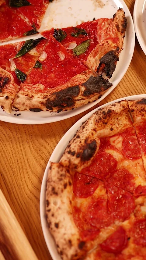 Hands Sharing Fresh Neapolitan Pizzas on a Wooden Restaurant Table 스톡 동영상 339514946