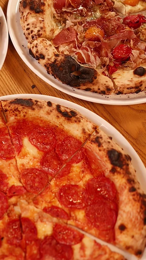 Hands Sharing Various Neapolitan Pizzas on a Wooden Restaurant Table 스톡 동영상 339513432