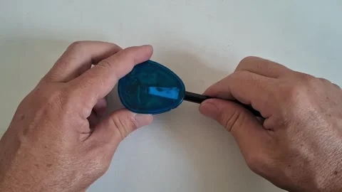 Hands sharpening a graphite pencil using blue plastic motion footage Stock Footage 339248236