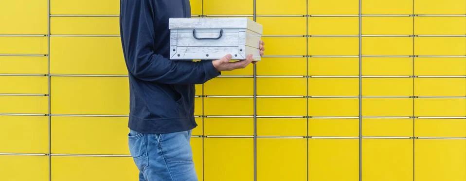 Hands with shipment to send using yellow self-service post terminal machine Foto stock
