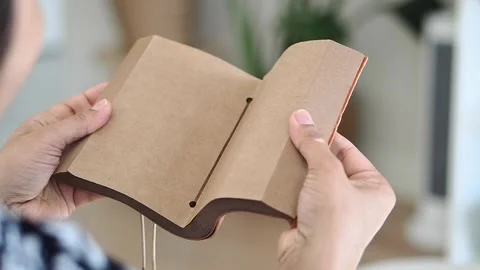 Hands show an empty brown notebook at a table Stock Footage 336769451