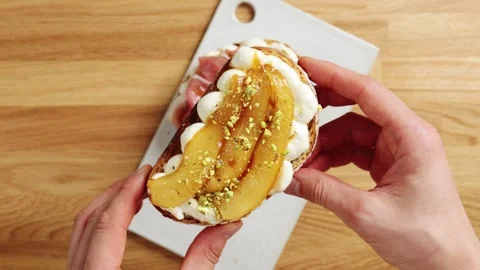 Hands show pear ricotta toast with nuts to camera. Video stock 344769751