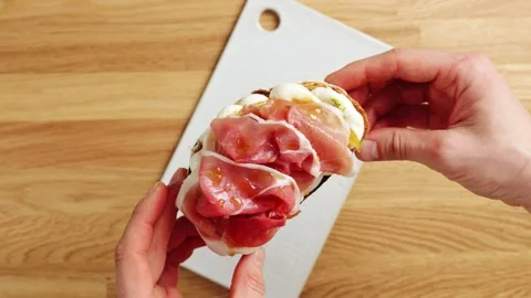 Hands show prosciutto ricotta toast to camera in timelapse. Video stock 344769760