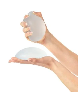 Hands showing and squeezing soft breast implant. Isolated, clipping path. Stock Photos