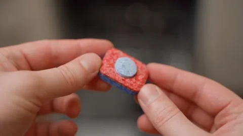 Hands showing colored dishwasher tablets, close-up on blurred background Stock-Footage 324700195