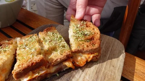 Hands showing ham and cheese toasted sandwich topped with oregano. Stock Footage 301367802
