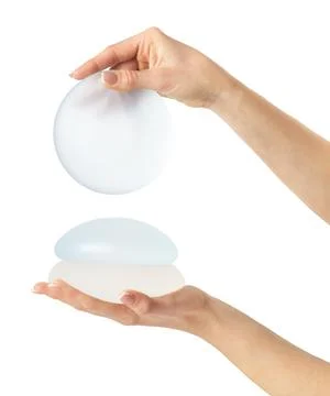 Hands showing round breast implants. Isolated on white background, clipping path Stock Photos