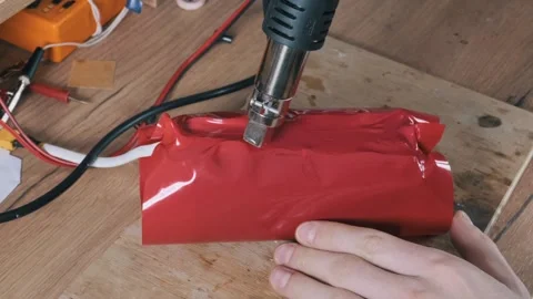 Hands Shrinking Red PVC Wrap On Lithium Battery Pack With Heat Gun Stock Footage 330296661