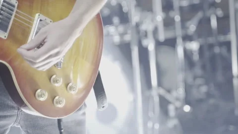 The hands of a singer playing a brown electric guitar on stage.  Stock Footage 266602373
