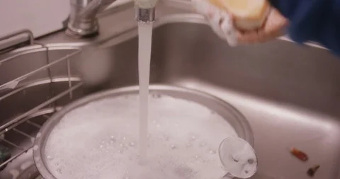 Hands in sink washing and cleaning dishes after a meal Stock Footage 123791126