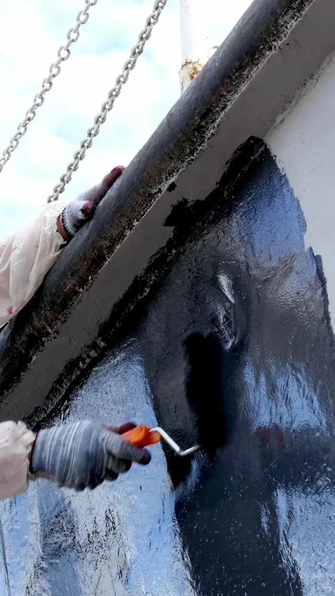 Hands skillfully apply fresh paint on a boat under a clear sky Stock Footage 298857053