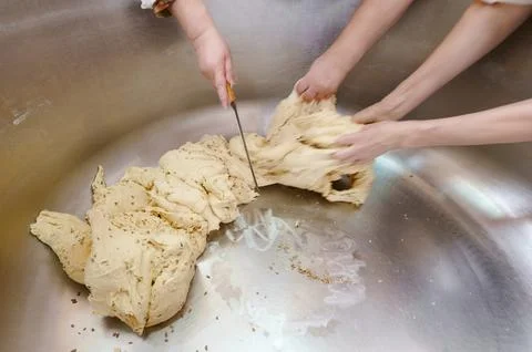 Hands skillfully knead and shape dough in a bustling kitchen, highlighting the Stock Photos