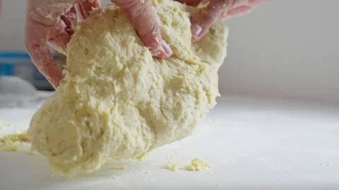 Hands skillfully kneading dough on a pristine surface, beautifully showcasing Stock Footage 314985952