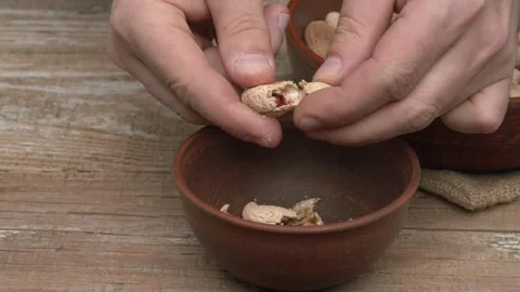Hands skillfully preparing a variety of nuts in a rustic brown bowl with care Stock Footage 291287438