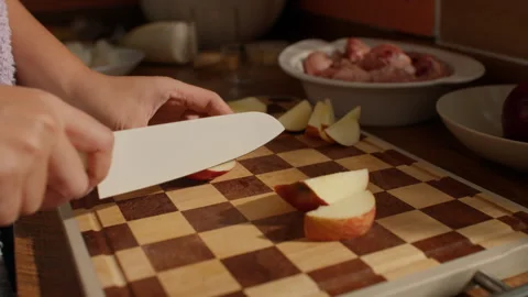 Hands Skillfully Slicing Fresh Apples on Checkered Cutting Board Stock Footage 331061493